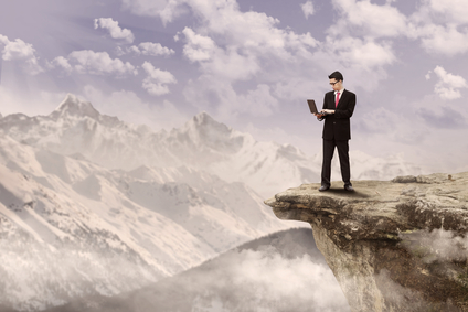 man standing on a cliff with a laptop